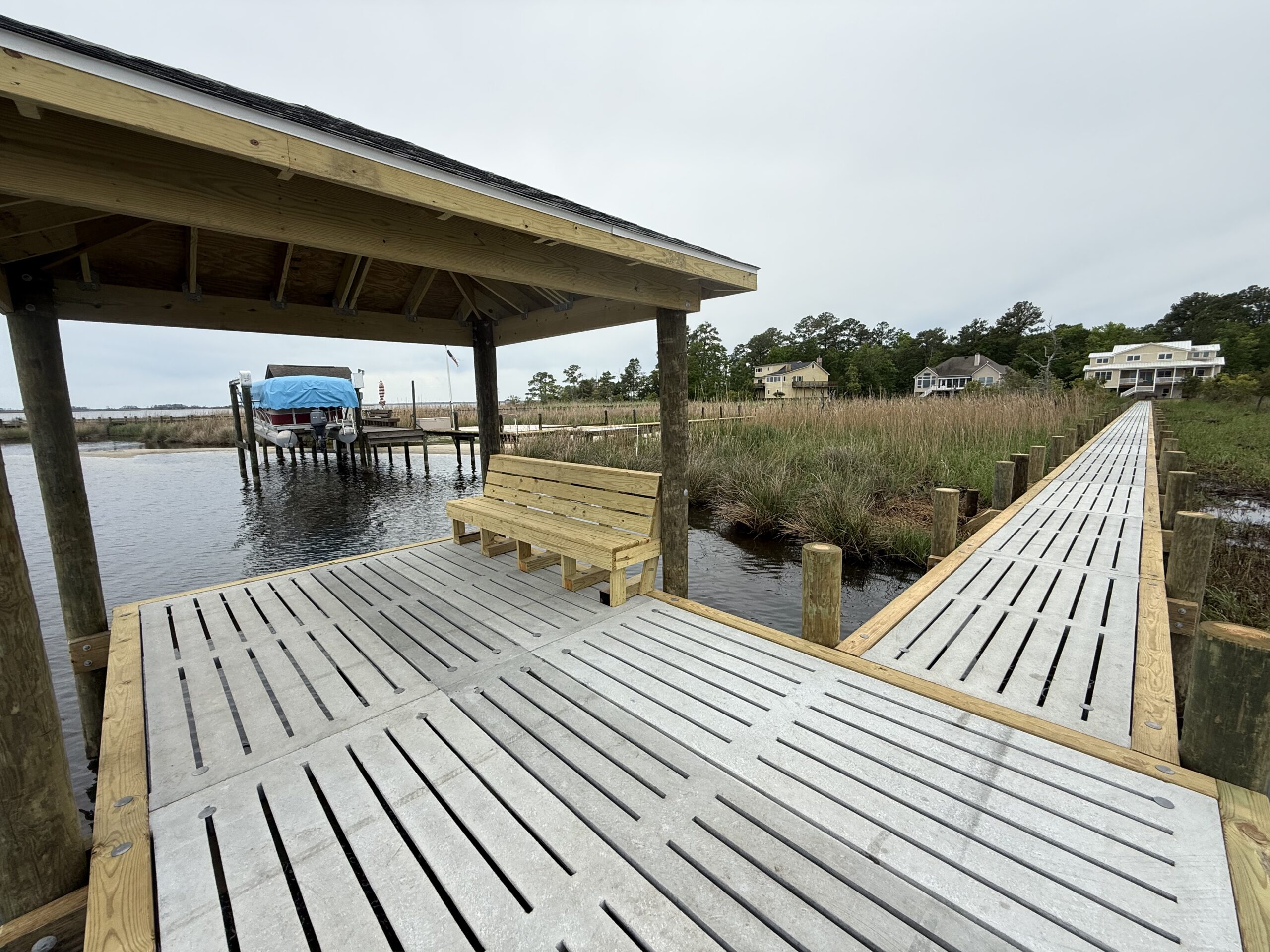 Concrete dock walkway built by Bobby Cahoon Marine Construction extending over marshland to a covered dock on the waterfront in Eastern North Carolina