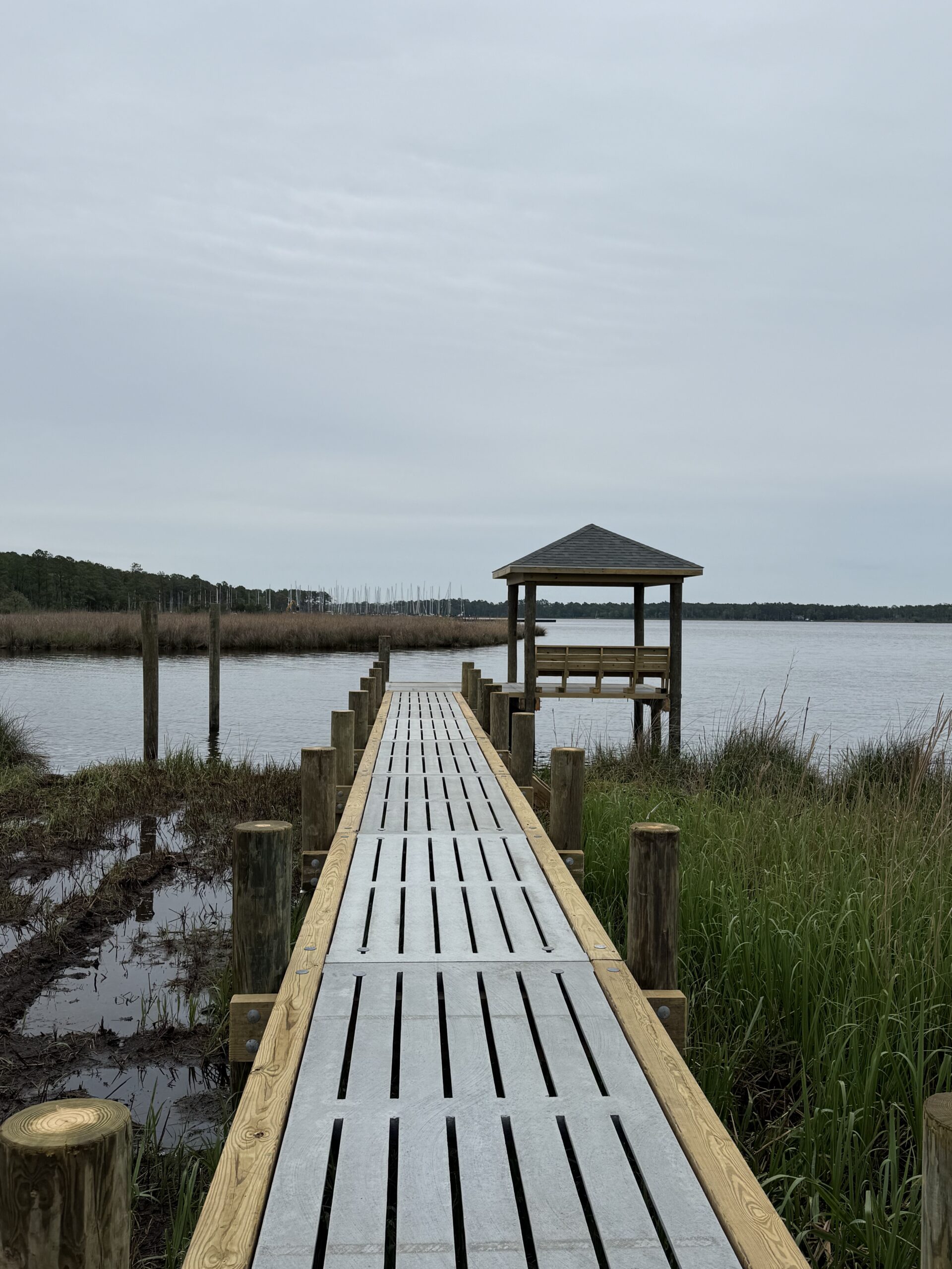 Concrete dock walkway built by Bobby Cahoon Marine Construction extending over marshland to a covered dock on the waterfront in Eastern North Carolina